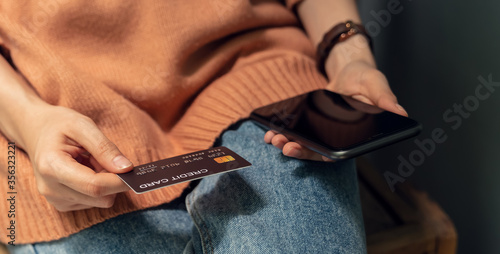 Woman holding smartphone and credit card with paying for shopping online.