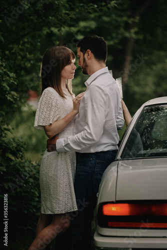 A guy and a girl are hugging next to a car. Romantic date evening walk. The relationship between people is love and tenderness. © ssergiocom