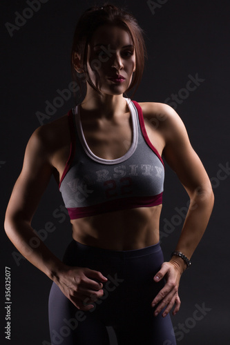 Fitness young woman in training clothes, dark backlit photo