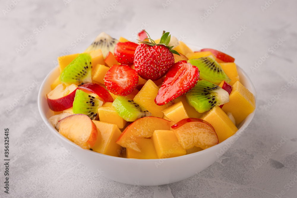 Close up of a bowl of fruit salad made of mango, kiwi, strawberry and peach Close up of a bowl of fruit salad made of mango, kiwi, strawberry and peach