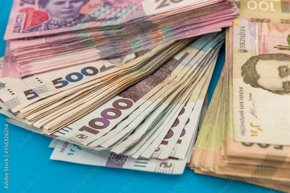 Ukrainian hryvnia money new bills 1000 and 500 isolated on blue. Stack of money. Ukrainian hryvnia money new bills 1000 and 500 isolated on blue. Stack of money.