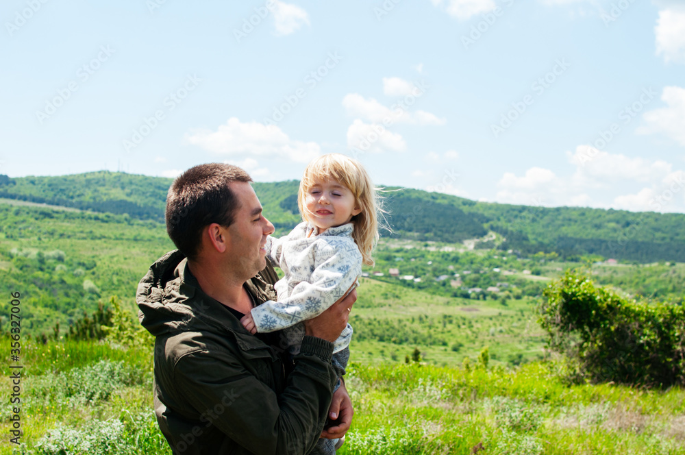 Joyful dad and daughter are playing outdoors in the park. The concept of a happy family. Dad with a baby.
