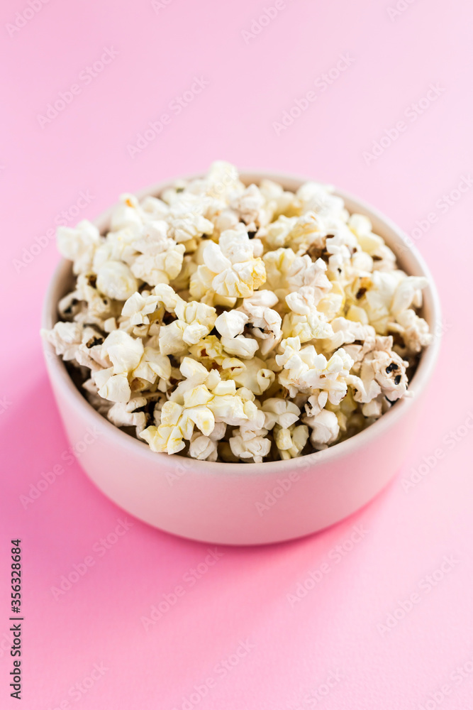 Popcorn in a pink bowl on pink background 45 degree angle close-up shot
