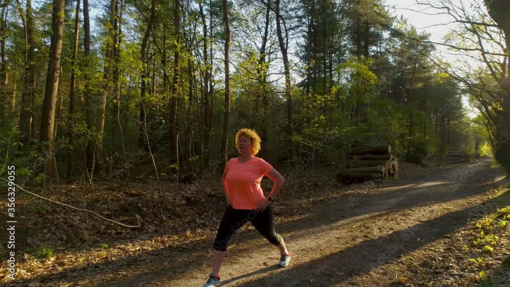 SLO MO WS Woman stretching on treelined dirt road / Breda, Noord-Brabant, Netherlands