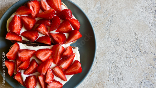 Toasts with cottage cheese and ripe strawberries on a blue plate. Light textured background. Healthy tasty breakfast. Top view. Copy space.