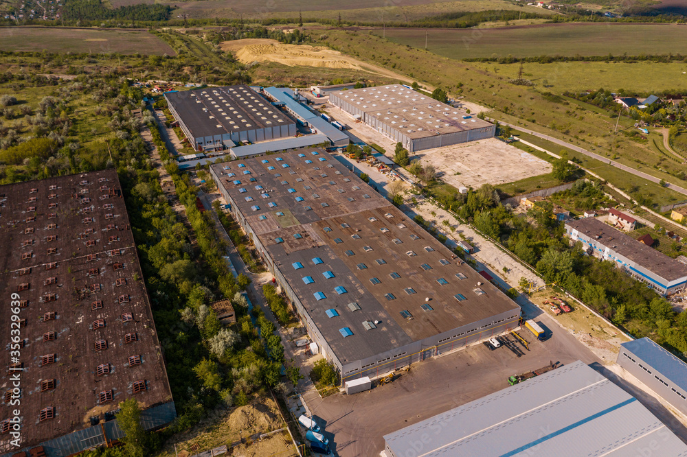 Aerial view of goods warehouse. Logistics center in industrial city zone from above. Aerial view of trucks loading at logistic center in agreen zone