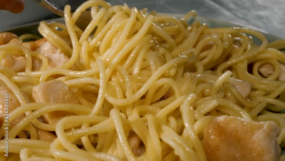 Wind on fork cooked noodles with chicken meat in plate. Homemade italian spaghetti food on domestic kitchen Wind on fork cooked noodles with chicken meat in plate. Homemade italian spaghetti food on domestic kitchen