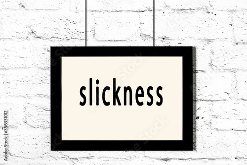 Valokuva Black frame hanging on white brick wall with inscription slickness