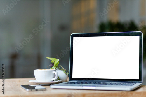 Mockup of laptop computer with empty screen with coffee cup and smartphone on table of the coffee shop background,White screen