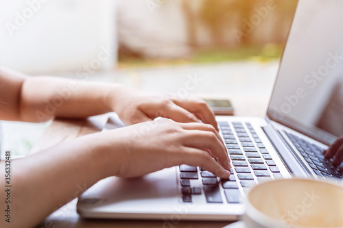 Close-up of freelance people business female casual working with laptop computer with coffee cup and smartphone in coffee shop like the background,communication concept