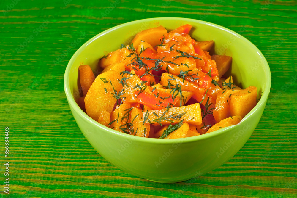 Potatoes with parsley in a green bowl on a wooden table. Boiled potatoes with orange sauce. Food in utensils on the background of an old pink board. Potatoes with parsley in a green bowl on a wooden table. Boiled potatoes with orange sauce. Food in utensils on the background of an old pink board.