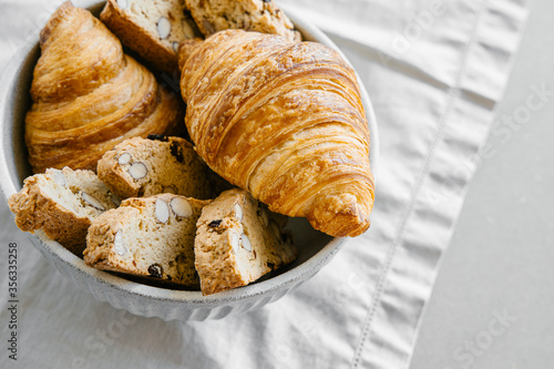 Freshly baked classic croissants and almond biscottis on linen light background. Breakfast food concept.  photo