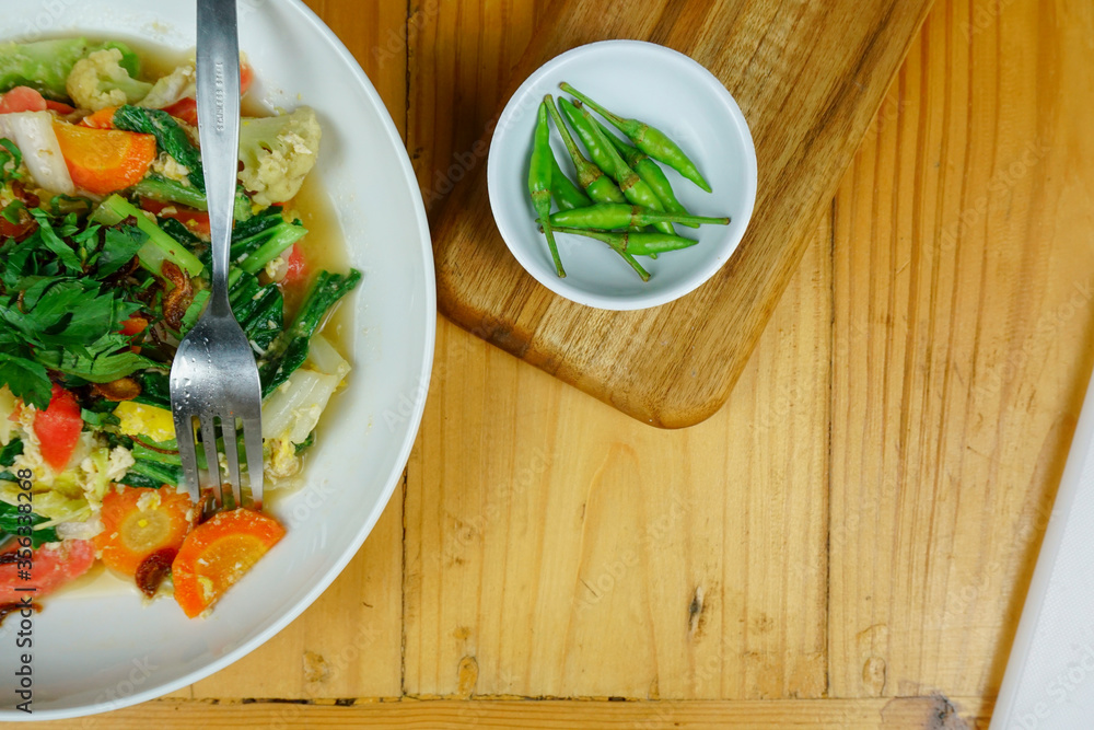 stir fried vegetable and some chilies on wooden background stir fried vegetable and some chilies on wooden background