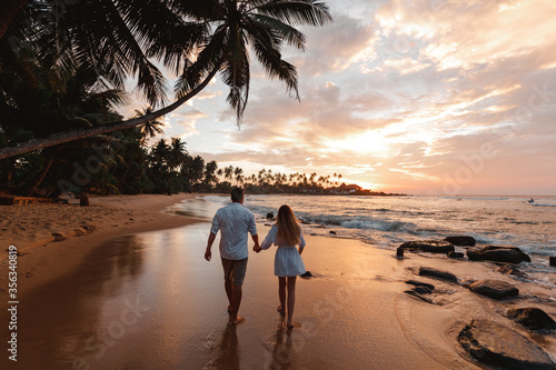 Fototapeta Naklejka Na Ścianę i Meble -  Happy Romanticjust married travel  Couple Enjoying Beautiful Sunset Walk on the Beach. Travel Vacation Retirement Lifestyle Concept