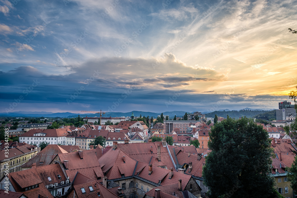 Ljubljana city on summer evening, Slovenia. Old house roofs in foreground. Dramatic colorful sky in background. Wide shot, HDR photography