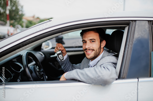 Side view of a young man holding key in his car
