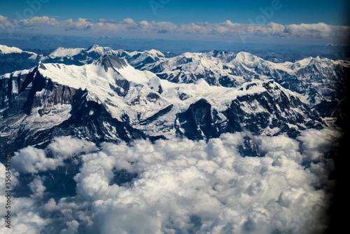 Aerial view of the Himalayas mountain ranges covered in snow and clouds as seen from an airplane window