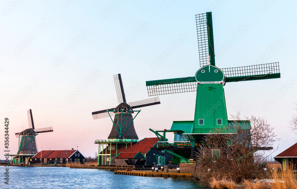Traditional Dutch windmills and handicraft workshops in the historical park open-air museum Zaanse Schans in the spring sunset. Netherlands, North Holland, Zaandam