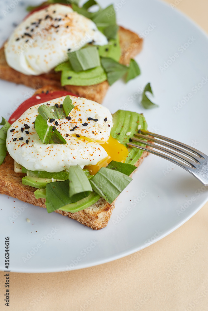 Breakfast toast with poached egg and avocado on the white plate Breakfast toast with poached egg and avocado on the white plate