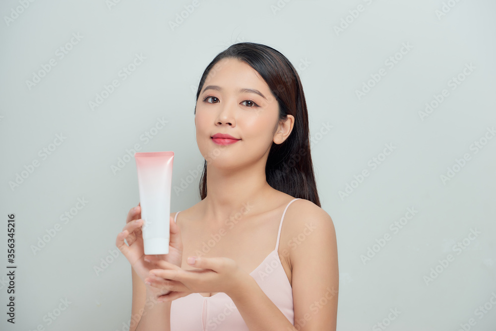 Beautiful portrait young asian woman holding and presenting cream or lotion product Beautiful portrait young asian woman holding and presenting cream or lotion product