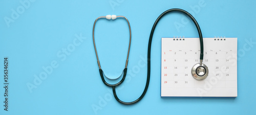 Stethoscope with calendar page date on blue background doctor appointment medical concept photo