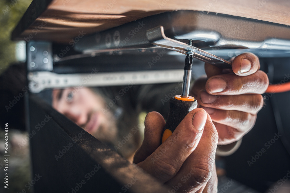 Hands of a mechanic with a screwdriver in a narrow space