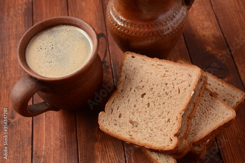 Traditional Russian or Ukrainian Malt Beer -Kvass in mug with rye bread on wooden table.