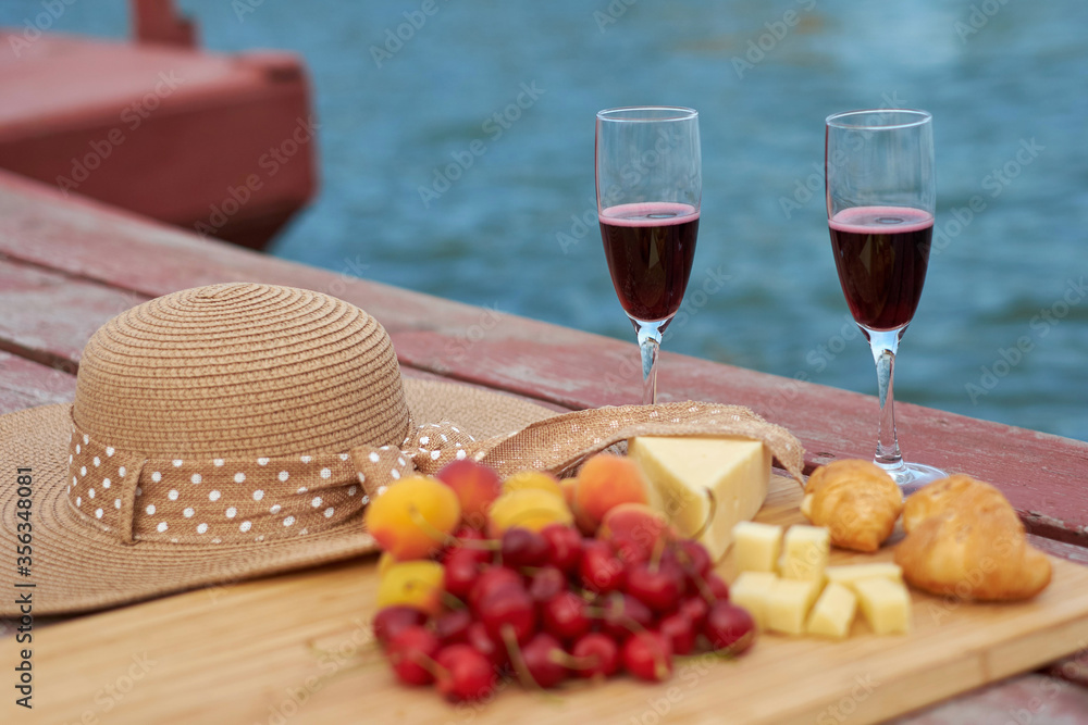 Two glasses of red wine, served outdoor with fruits and beautiful blue ocean view.