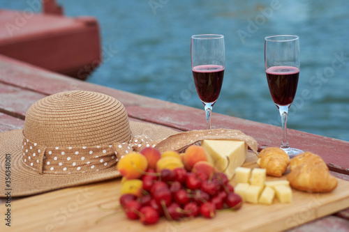 Two glasses of red wine, served outdoor with fruits and beautiful blue ocean view.
