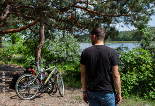 man near a bicycle near a lake in the forest © dyachenkopro