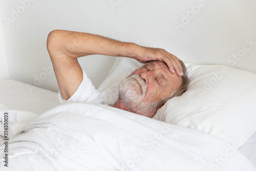 Worried senior retirement man lying awake in his bed