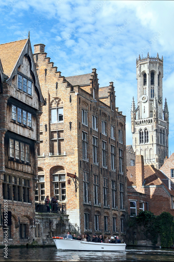 Bruges, Belgium - March 27, 2015 - view with canal of the beautiful old buildings and the tower of the cathedral
