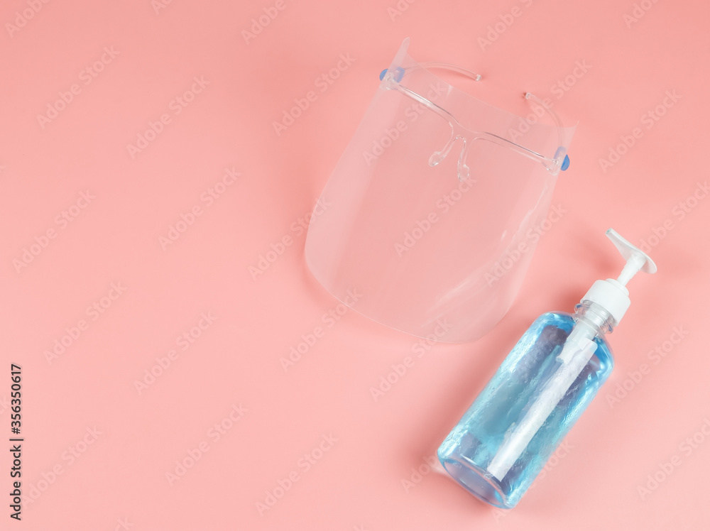 COVID-19 prevention and new normal lifestyle concept. Top view of face shied and alcohol hand sanitizer gel on pink background. COVID-19 prevention and new normal lifestyle concept. Top view of face shied and alcohol hand sanitizer gel on pink background.