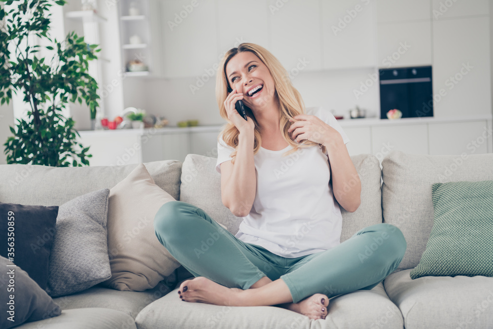 Photo of domestic cheerful beautiful blond lady sit couch hold telephone chatting talking friends family relatives quarantine stay home good mood legs crossed living room indoors Photo of domestic cheerful beautiful blond lady sit couch hold telephone chatting talking friends family relatives quarantine stay home good mood legs crossed living room indoors