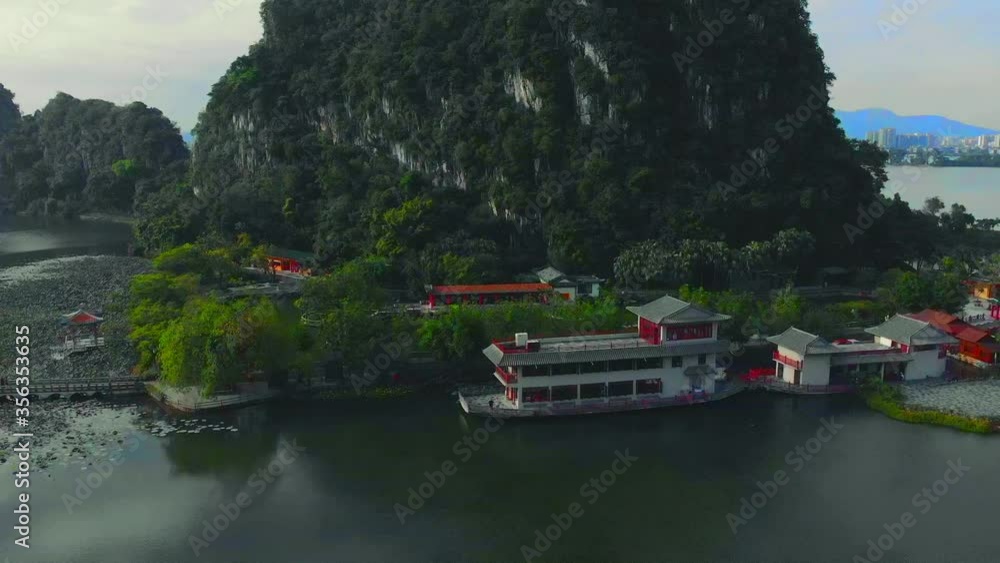 A reveal of a beautiful mountain just behind a boathouse on a small lake. In zhaoqing, China A reveal of a beautiful mountain just behind a boathouse on a small lake. In zhaoqing, China