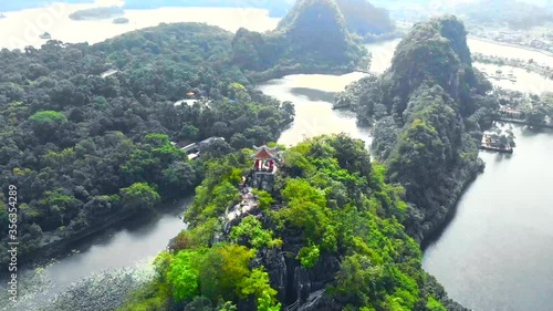 A fly out drone reveal and swirl of a gazebo on the top of a mountain next to water and the city of zhaoqing, China. photo