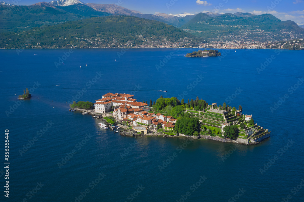 Isola Bella is located on Lake Maggiore in Italy. Boats in motion on the water. Magnificent garden Borromee in the background the alps in the snow, clouds in the blue sky.