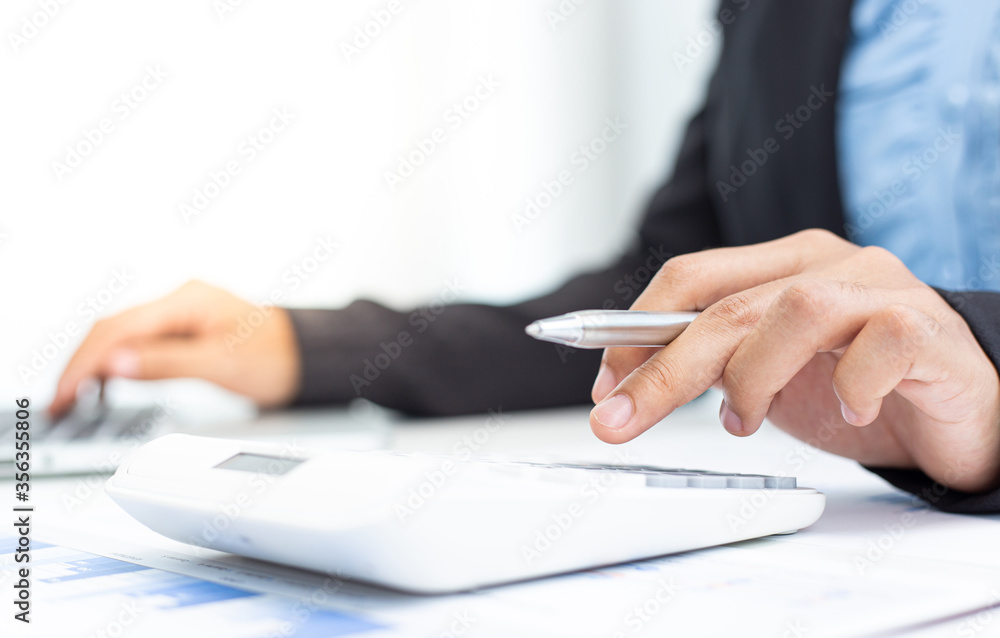 Businesswomen are calculating finances and analyzing market data with graphs and laptops at work, Business Financing Accounting Banking and tax system Concept. Businesswomen are calculating finances and analyzing market data with graphs and laptops at work, Business Financing Accounting Banking and tax system Concept.