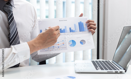 Marketing businessmen are analyzing financial and insights strategies for generating revenue including corporate income tax with laptops and graphs in the office, Finance and Accounting concept.