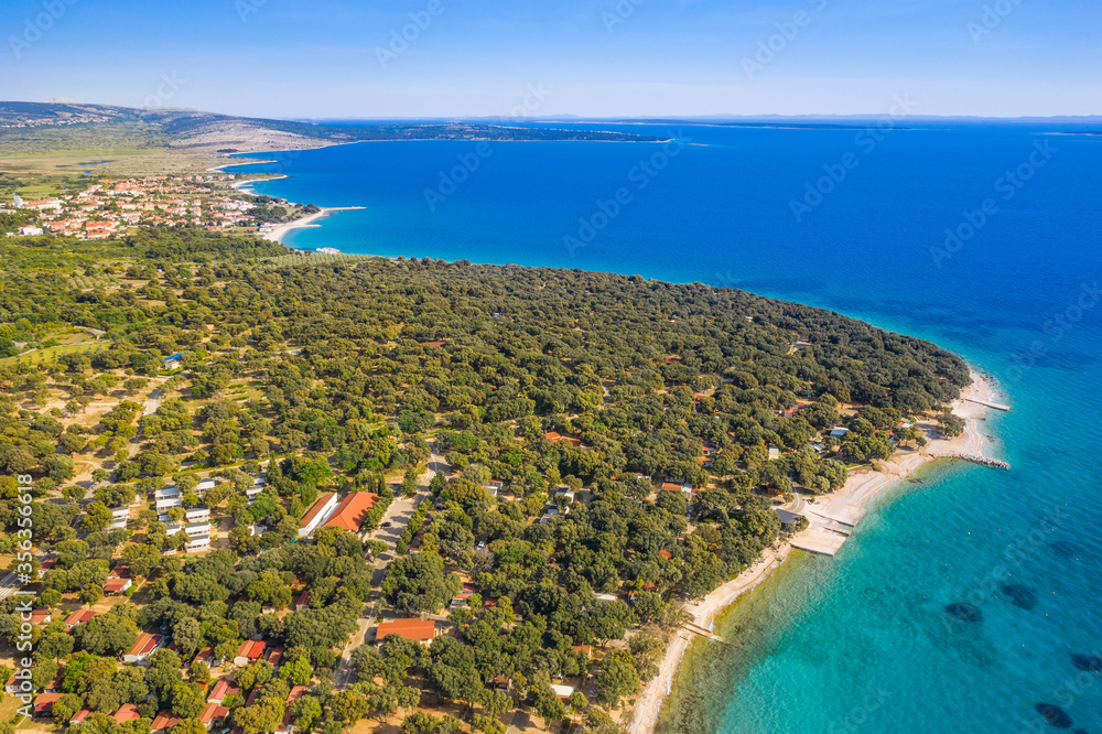 Croatia, island of Pag, beautiful touristic resorts, long beaches under pine trees, turquoise water of Adriatic Sea on sunny summer day. Aerial drone view.