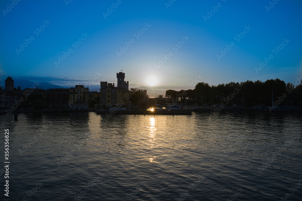 Sunrise over Sirmione, Lake Garda Italy. Blue sky, trail from the sun on the water. Aerial view
