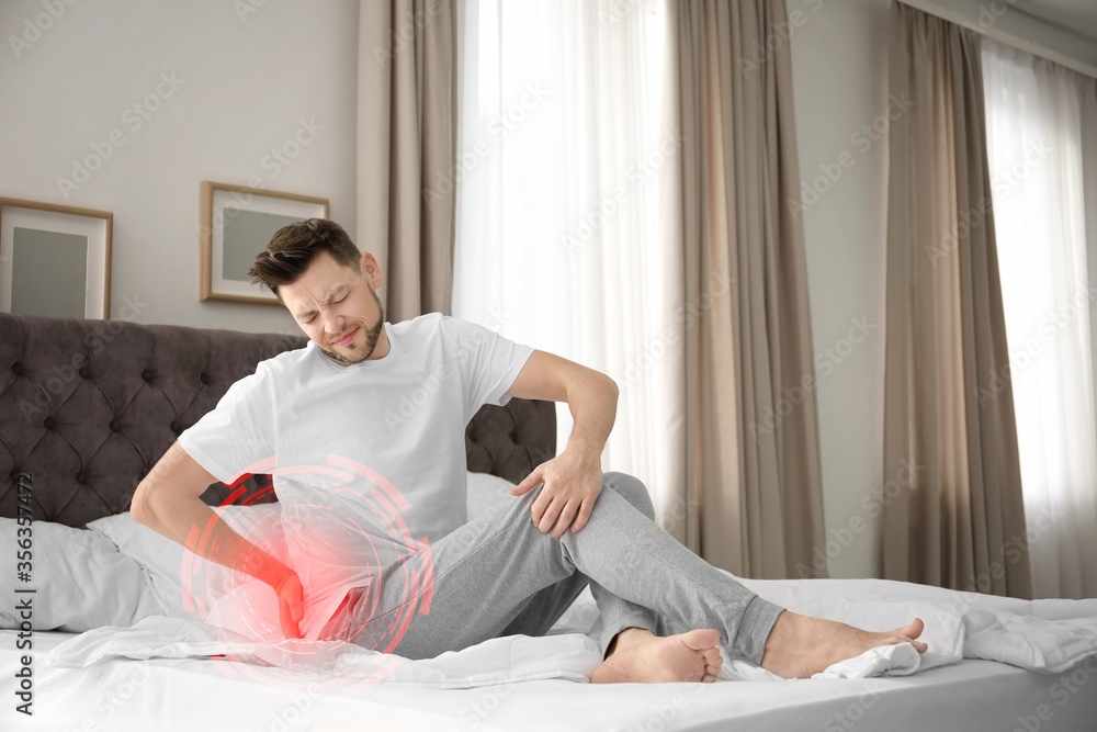 Man suffering from back pain after sleeping on uncomfortable mattress at home Man suffering from back pain after sleeping on uncomfortable mattress at home