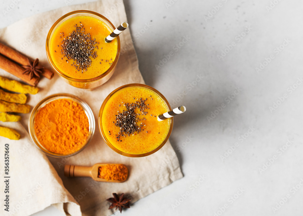 Turmeric smoothie in glass with ingredients, curcumin poweder, ginger and spice on white Turmeric smoothie in glass with ingredients, curcumin poweder, ginger and spice on white