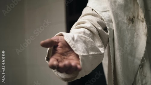 Jesus wearing a white robe extends his hand in slow motion photo