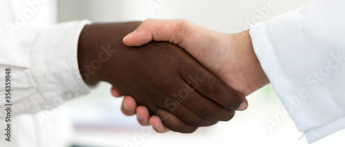 Image of african american people black skin and caucasian white skin people partners successful handshake together.friendship and respect concept