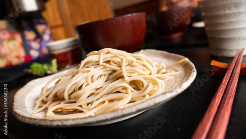Cold soba (buckwheat noodles) with wooden chopsticks. Close up of traditional Japanese cuisine.   