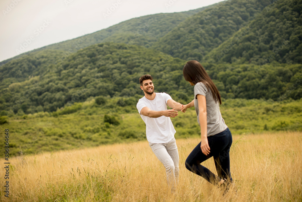 Happy young couple in love walking through grass field