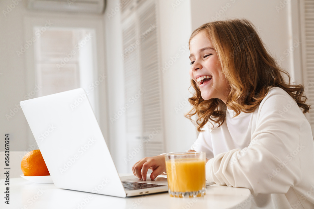 Photo of cheerful cute girl typing on laptop and laughing Photo of cheerful cute girl typing on laptop and laughing