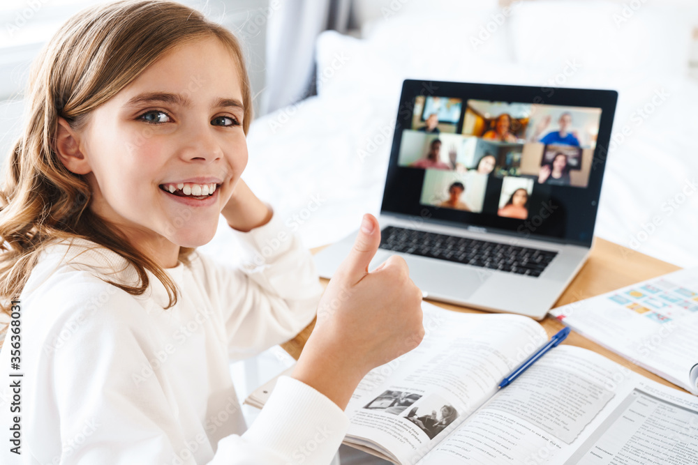 Photo of caucasian excited girl showing thumb up while studying online Photo of caucasian excited girl showing thumb up while studying online