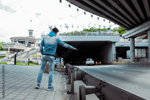 Εκτύπωση καμβά Back view of hitchhiker stopping car near road on urban street